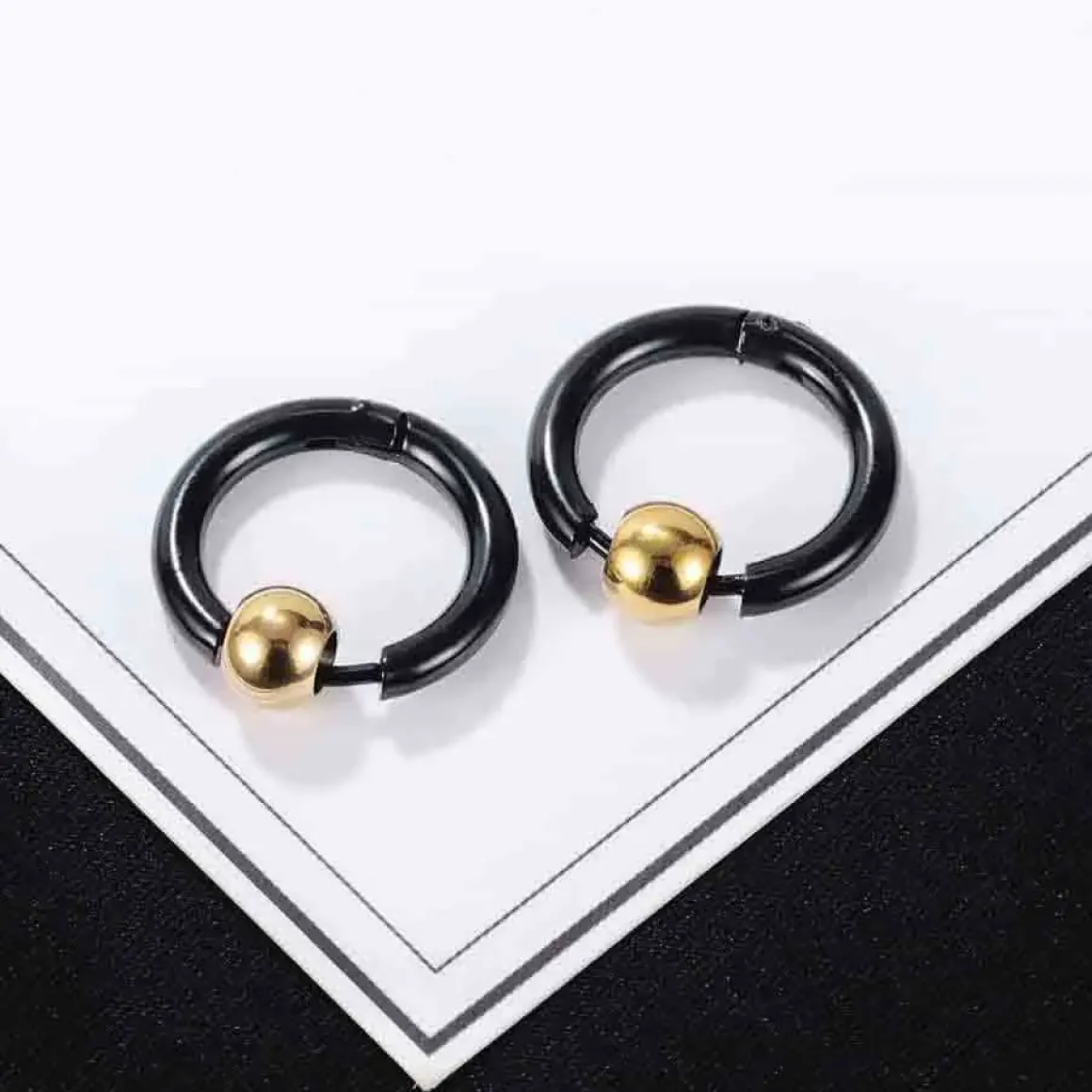 Sort ørering i stål med gylden kugle.